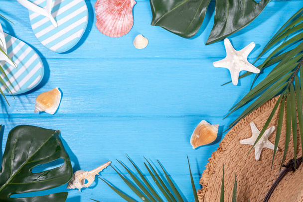 Καλοκαιρινές διακοπές με ψάθινο καπέλο, σαγιονάρες, καλοκαιρινά αξεσουάρ, διακόσμηση με σεζλόνγκ και τροπικά φύλλα - Φωτογραφία, εικόνα