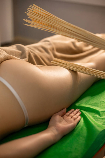 Hieroja tekee bambu luuta hieronta naiselle kylpylä menettelyn aikana - Valokuva, kuva