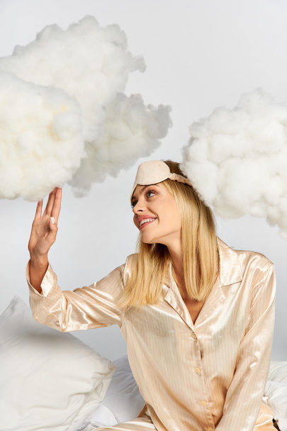 Appealing woman in cozy pyjamas surrounded by clouds. - Photo, Image