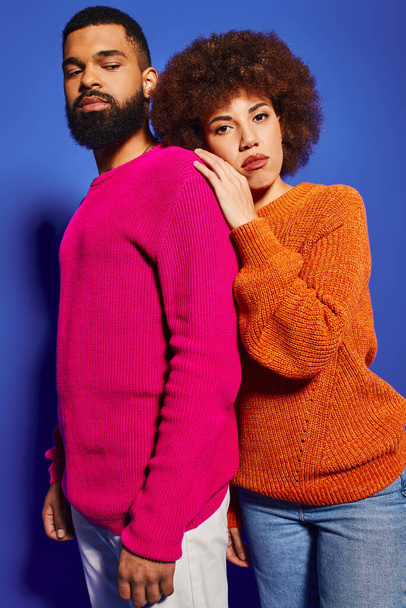 Jonge man en vrouw, vrienden, samen staan in levendige casual kleding tegen een blauwe achtergrond, presentatie van vriendschap. - Foto, afbeelding