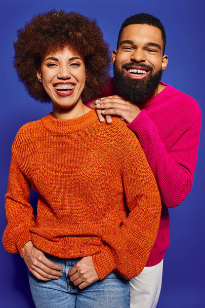 Jonge Afro-Amerikaanse vrienden in levendige casual kleding staan samen op een blauwe achtergrond, portretteren de essentie van vriendschap en eenheid. - Foto, afbeelding