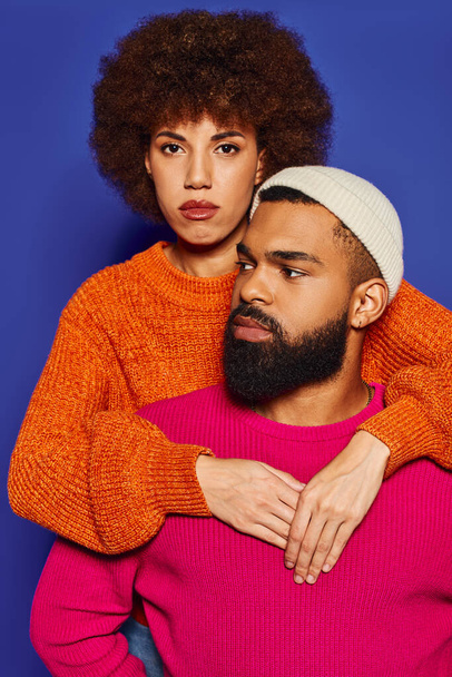 Ein junger Mann mit Bart und eine Frau im Pullover, die ein starkes Band der Freundschaft auf blauem Hintergrund zeigt. - Foto, Bild