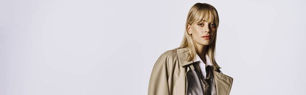 Stylish woman posing in trench coat on white backdrop. - Фото, изображение