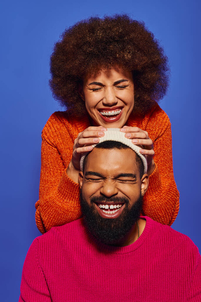 Una joven afroamericana sosteniendo una cabeza masculina, sonriendo, mostrando amistad y conexión. - Foto, Imagen