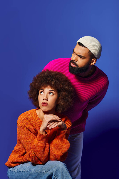 A man and woman, friends, strike a pose in vibrant casual attire against a blue background. - Photo, Image