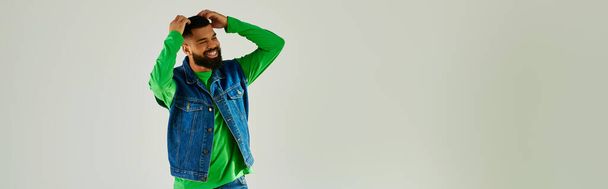 Чоловік з бородою в зеленому довгому рукаві і блакитних джинсах. - Фото, зображення