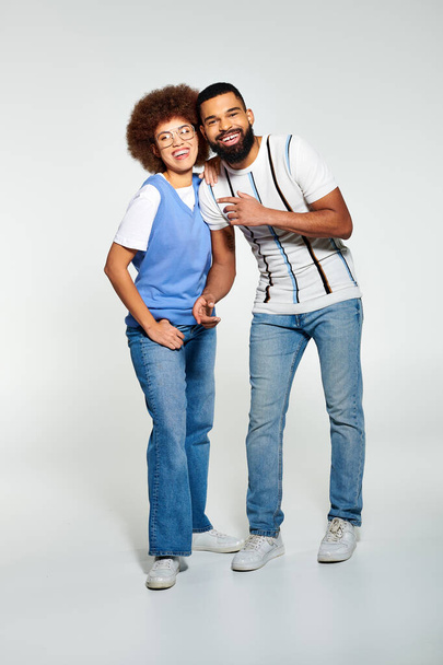 Un hombre y una mujer afroamericanos en atuendo de moda posando juntos sobre un fondo gris. - Foto, imagen