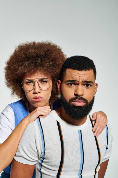 Афроамериканец мужчина и женщина в модном наряде позируют вместе на сером фоне, символизируя дружбу. - Фото, изображение