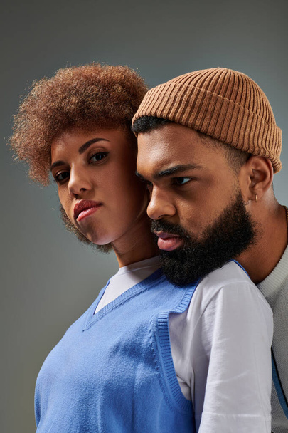 Un hombre y una mujer afroamericanos, vestidos con ropa elegante, posan juntos sobre un fondo gris. - Foto, imagen