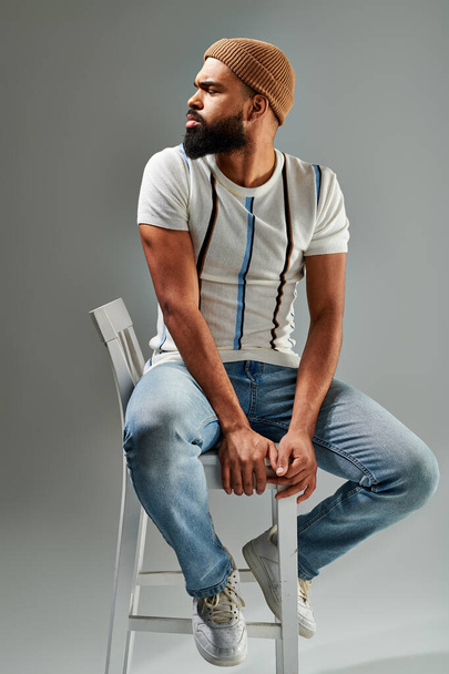 Человек с бородой задумчиво сидит на стуле, погруженный в размышления, источая чувство мудрости и самоанализа.. - Фото, изображение