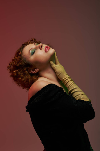 Curvy redhead in bodysuit and gloves striking pose - Valokuva, kuva