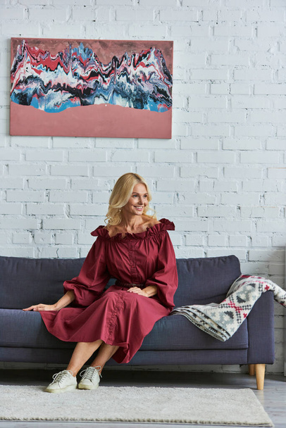 Stylish woman in red dress sitting on a couch. - Photo, Image