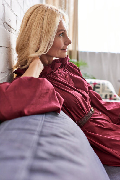 Stylowa kobieta na kanapie w jasnoczerwonej sukience. - Zdjęcie, obraz