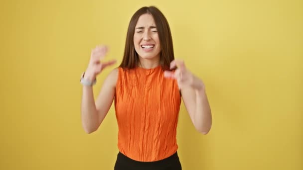 Woedende jonge Spaanse vrouw in gele studiokamer, staande, schreeuwend in mouwloos t-shirt. ruwe emotie, verhoogd armgebaar, wat frustratie betekent. gekke uitdrukking, indoor geïsoleerde achtergrond. - Video