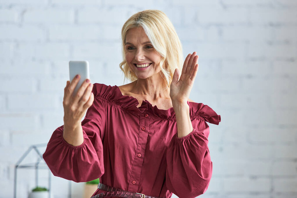 Κομψή γυναίκα με κομψή ενδυμασία βγάζει selfie με το κινητό της. - Φωτογραφία, εικόνα