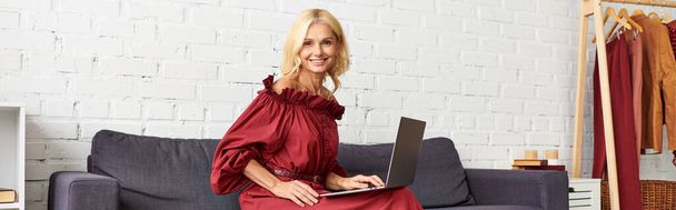 Felnőtt nő stílusos ruhában laptoppal a kanapén. - Fotó, kép
