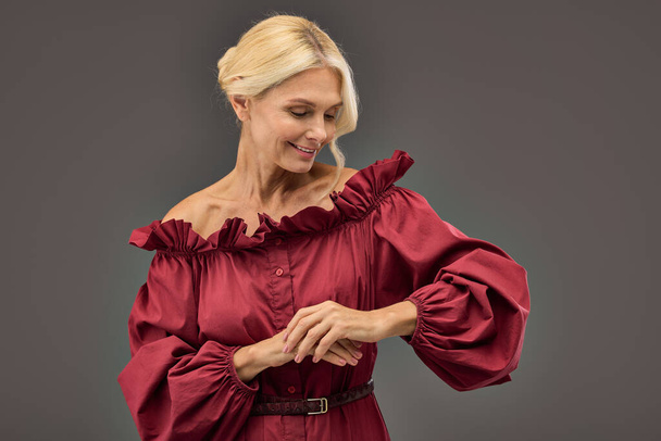 Зрелая элегантная женщина в красном шикарном платье тепло улыбается. - Фото, изображение