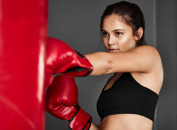 Bag, boxer or woman punching in boxing training, exercise or workout in gym studio for wellness. Sports, female athlete or strong girl fighting with red gloves, fitness or power on grey background. - Photo, Image