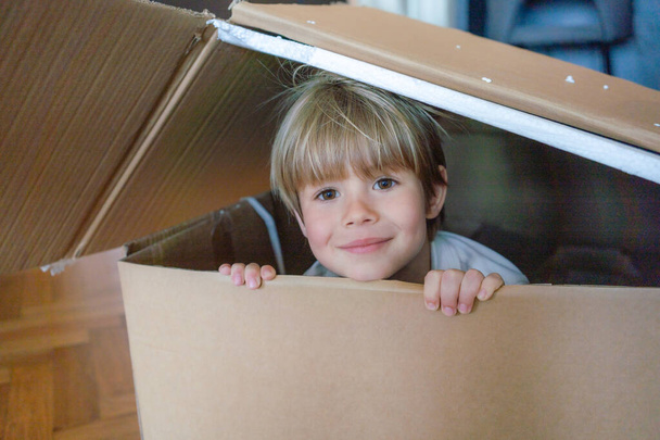 Pieni poika pitää hauskaa pahvilaatikon kanssa. Leikkisä childhood.child sisällä sarjakuva laatikko. - Valokuva, kuva