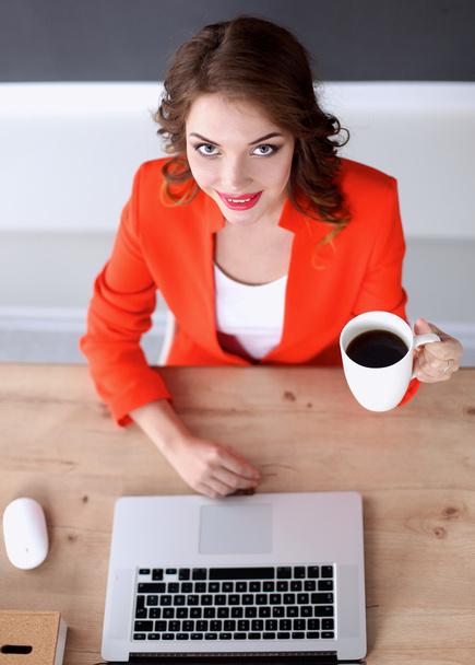 Attractive woman sitting at desk in office, working with laptop - Photo, image