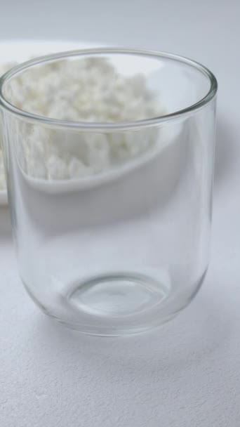 Pouring milk in glass from a bottle on a light background. Breakfast food and dessert. Healthy and Dairy product concept. Close up, vertical footage - Footage, Video