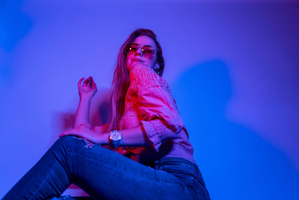 Alta moda mulher modelo em luzes coloridas de néon azul e roxo brilhante posando em estúdio. Retrato de mulher bonita com maquiagem brilhante na moda. Design de arte estilo vívido - Foto, Imagem