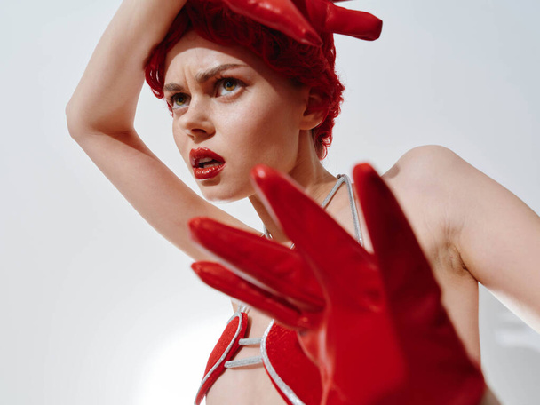 Kışın moda çekimlerinde kırmızı eldivenli ve elleri başının üstünde kırmızı şapkalı bir kadın. - Fotoğraf, Görsel