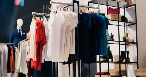 Modern boutique filled with casual wear, multiple racks with fashionable merchandise. Interior of empty clothing store with new fashion colletion on hangers. Small business concept. - Photo, Image