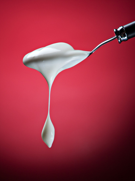 Spoon with yogurt on red - 写真・画像