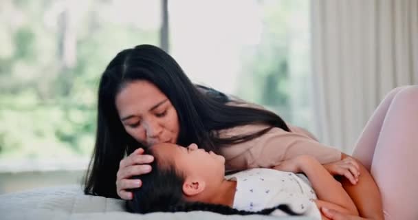 Happy mother, kiss and playing with child on bed for support, care or embrace in relax together at home. Mom, daughter or young kid with smile for affection, playful holiday or weekend in bedroom. - Footage, Video