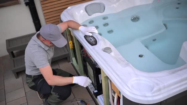 Een man wordt getoond die aan een hot tub werkt, lekken repareert, onderdelen vervangt en het systeem schoonmaakt. Het proces omvat gereedschappen, apparatuur en technische knowhow om ervoor te zorgen dat de hot tub goed functioneert. - Video