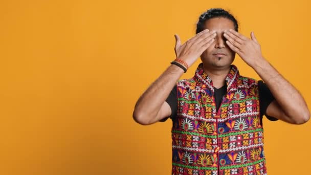 Man wearing traditional indian clothing covering eyes, ears and mouth, imitating three wise monkeys, doing dont see, dont hear and dont speak hand gesturing concept, studio background, camera A - Footage, Video