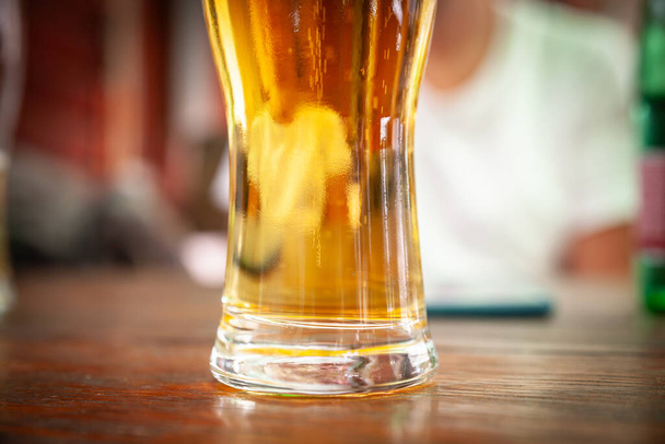 Selective blur on a Closeup on a beer mug containing a light beer, pilsner / lager style, served in a standard pint size glass. - Photo, Image