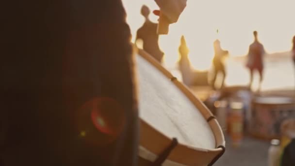 Una persona sostiene un tambor y el tambor es blanco. El tambor está en primer plano y el fondo tiene gente - Metraje, vídeo