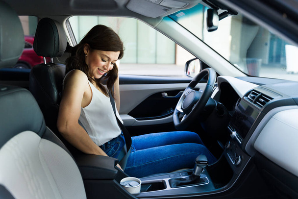 Oldalnézet egy gyönyörű nő csatolja be magát, és rögzíti a biztonsági övét egy autóban vezetés előtt - Fotó, kép