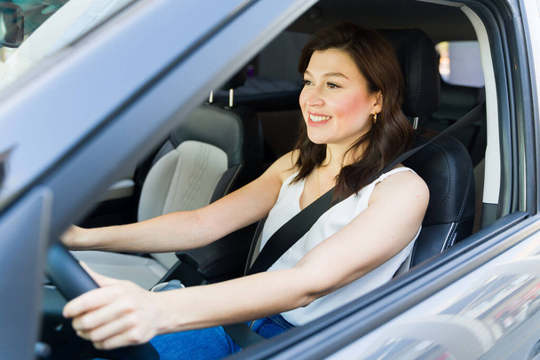 Donna sorridente concentrata sulla strada durante la guida della sua auto, raffigurante indipendenza e comfort nella gestione del veicolo - Foto, immagini