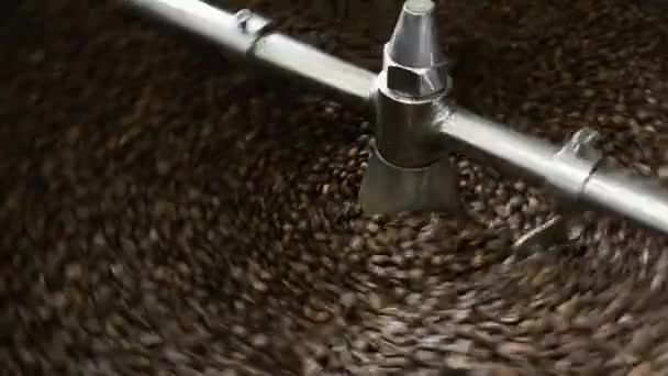Friss sült kávébab előállítása. A Sült Mester kinyitja a kávéfőzőt. A pörkölt kávébab leesik egy sütő hűtő tányérjára. - Felvétel, videó