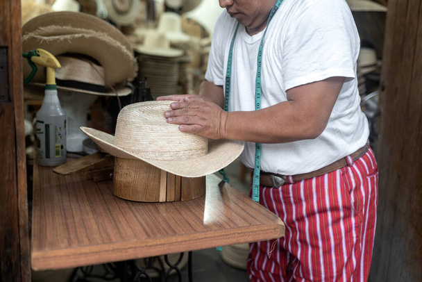 Yetişkin bir İspanyol, Guatemala 'da geleneksel bir atölyede ahşap bir blokla doğal bir fiber şapka yapıyor. - Fotoğraf, Görsel