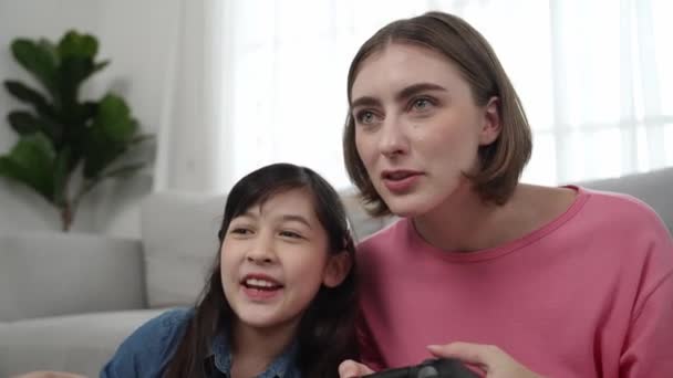 Girl winning game while caucasian mom clapping hands to celebrate successful achievement while sitting at living room. Attractive mother and daughter spend time together while hold joystick. Pedagogy. - Footage, Video