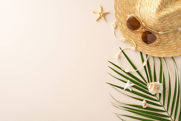 Примите солнечные ощущения: верхний вид соломенной шляпы, солнцезащитные очки, островное ожерелье, пальмовые листья, раковины и морские звезды на пастельно-бежевом, создавая настроение для летних постов - Фото, изображение