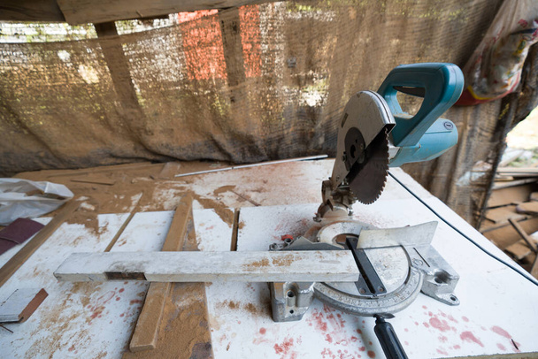 Ένα σύνθετο πριόνι μίξερ τοποθετείται σε ένα τραπέζι εργασίας με ξύρισμα ξύλου και τυπικά συντρίμμια κατασκευής γύρω από αυτό.  - Φωτογραφία, εικόνα