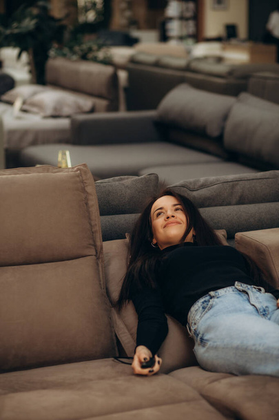 uma mulher escolhe um sofá com um massageador para sua casa - Foto, Imagem