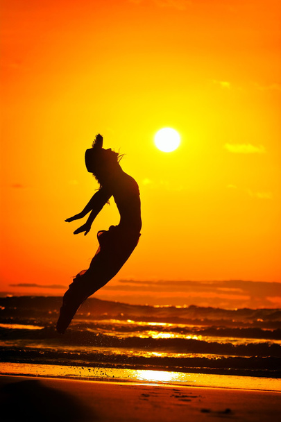 junge Frau springt an einem Sommerabend am Strand - Foto, Bild