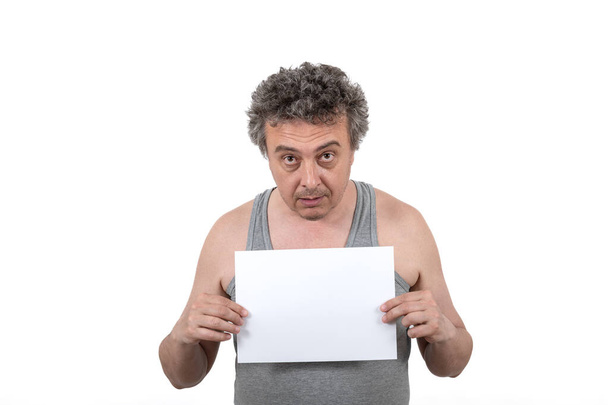 Un uomo di mezza età dai capelli grigi shaggy con stoppie in una t-shirt senza maniche tiene un segno bianco senza un'iscrizione nelle sue mani - Foto, immagini