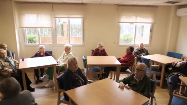 Увеличение замедленного движения пожилых людей, сидящих за столиками в светлом помещении дома престарелых в дневное время - Кадры, видео