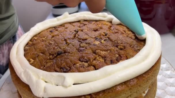 Een persoon gebruikt een piping bag om een taart vorst, het toevoegen van de finishing touch aan een heerlijke gebakken goederen recept voor een zoete traktatie - Video