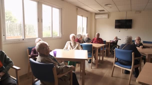 Zoom al rallentatore delle persone anziane sedute ai tavoli nella stanza della luce della casa di vecchiaia durante il giorno - Filmati, video