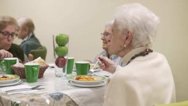 Zeitlupe älterer Frauen, die um den Tisch sitzen und in der Kantine des Altenheims leckeres Abendessen essen - Filmmaterial, Video