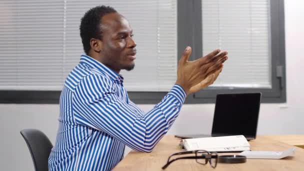 Skoncentrowany afrykański menedżer siedzi w nowoczesnym biurze i rozmawia. Pracownik myśleć o sprawach biznesowych, rozwiązanie wyszukiwania, zrobić on-line badania rynku finansowego, kreatywnej telepracy - Materiał filmowy, wideo