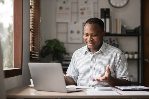 Afro-Amerikaanse zakenman werkt met laptop, online vergadering en presentatie van resultaten via Zoom online.. - Foto, afbeelding